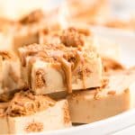 Slices of Biscoff Fudge stacked on a white plate.