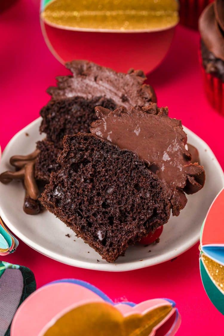 A chocolate cupcake sliced in half on a white plate.