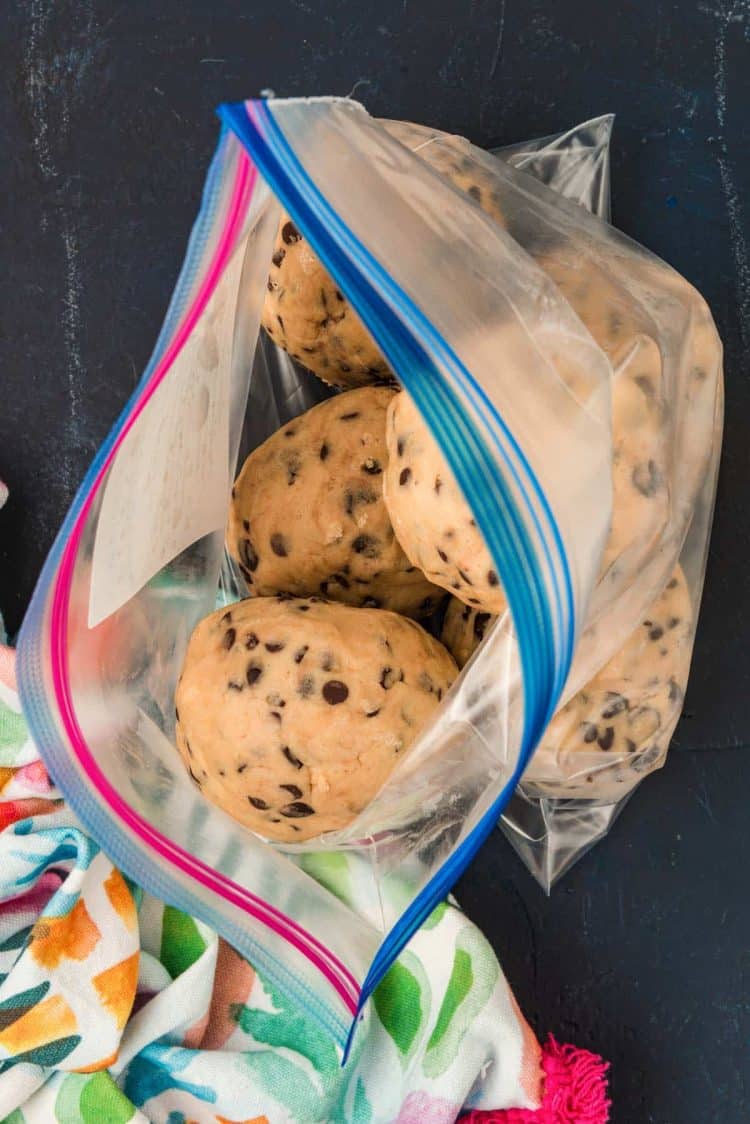 Balls of frozen cookie dough being added to a large ziploc bag.