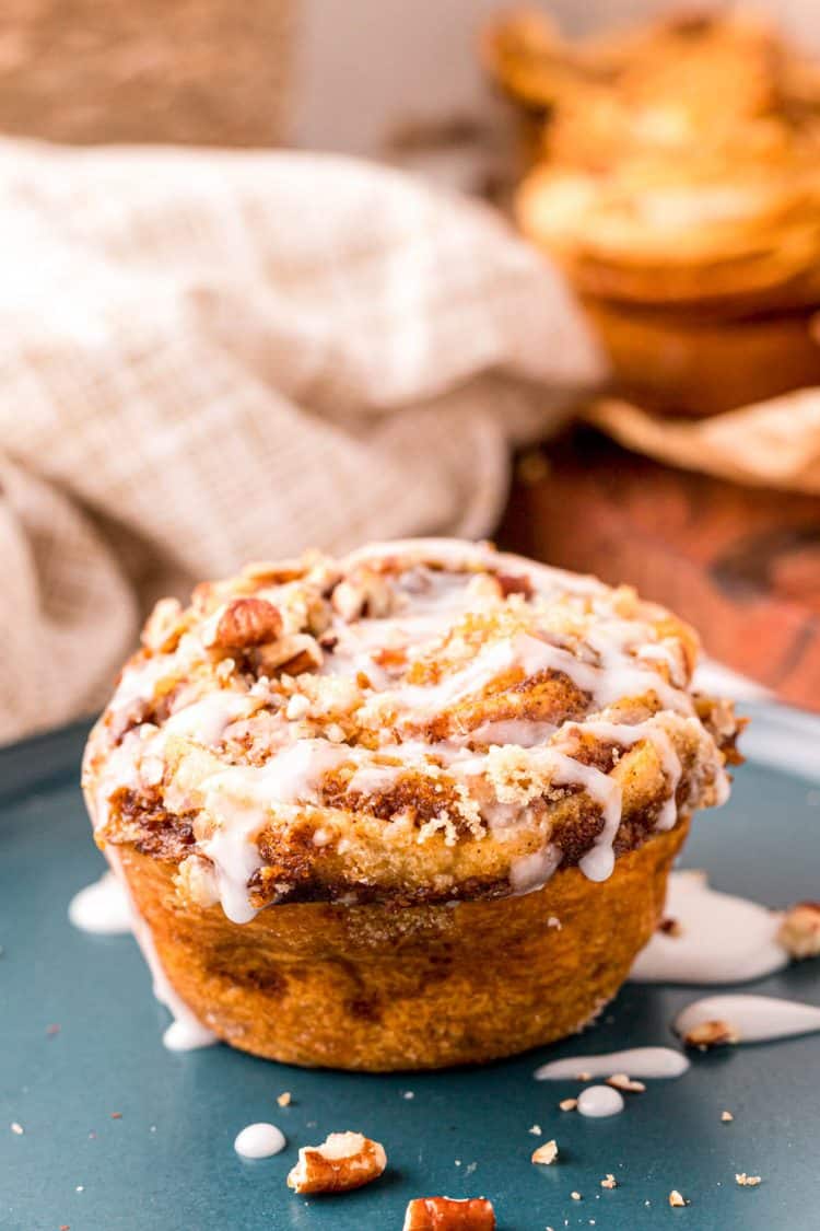 Pumpkin Cinnamon Roll Muffin with icing on a blue plate.