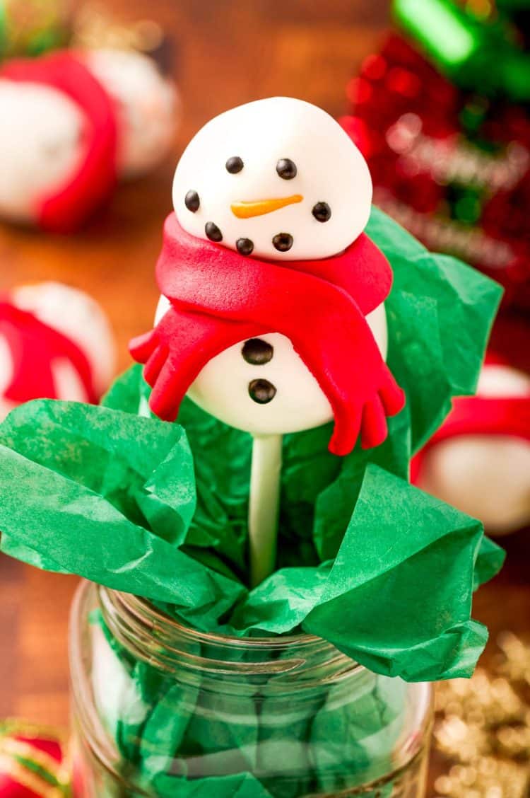 Snowman cake pop in a mason jar with green tissue paper.