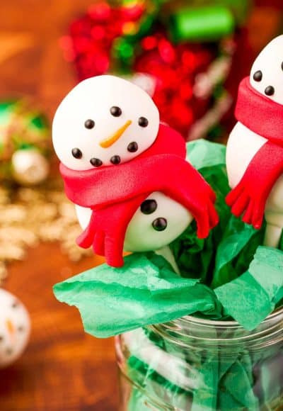 Snowman cake pop in a mason jar with green tissue paper.