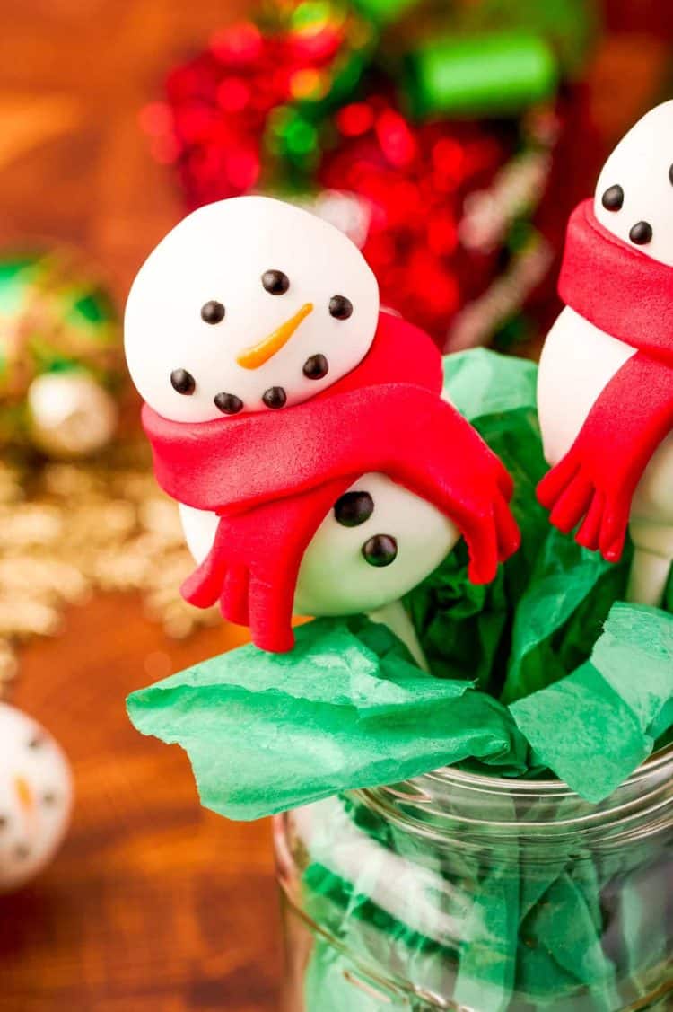 Snowman cake pop in a mason jar with green tissue paper.