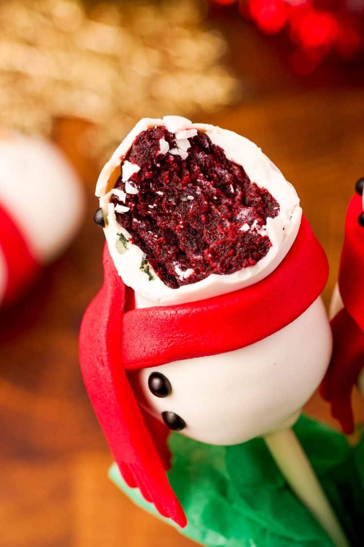 Snowman cake pop with a bite in it to reveal the red velvet center.