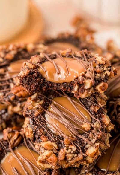 Close up of Chocolate Turtle Thumbprint Cookies piled on top of each other.