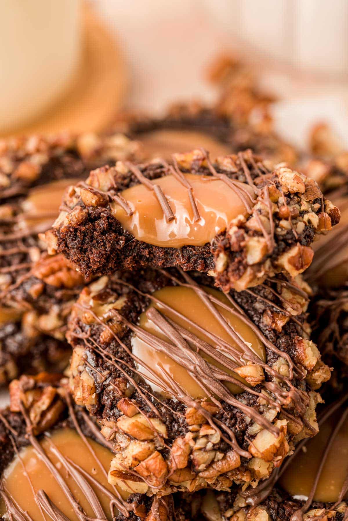 Close up of Chocolate Turtle Thumbprint Cookies piled on top of each other.