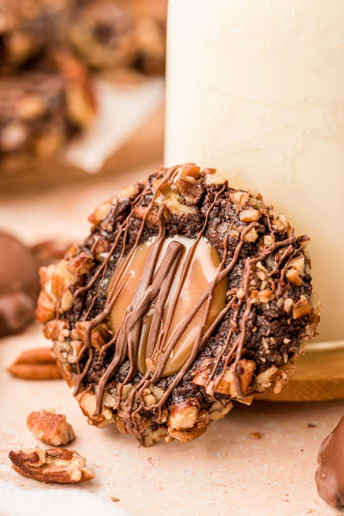 A turtle thumbprint cookie leaning against a bottle of milk.