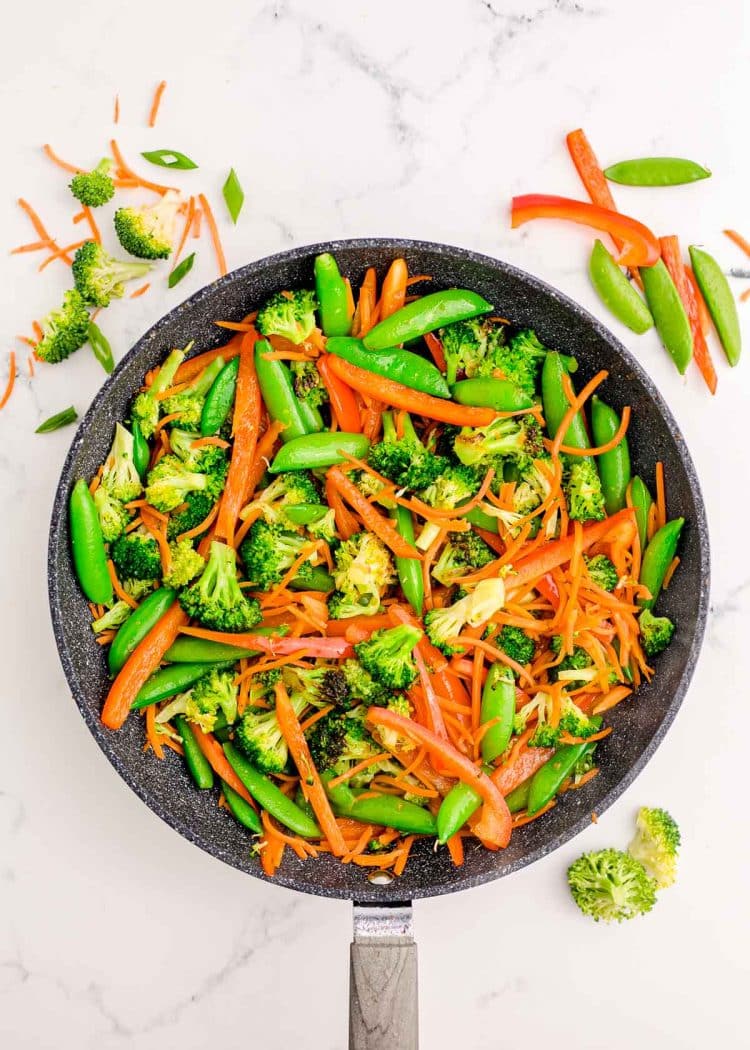 Vegetables being sauteed in a skillet.