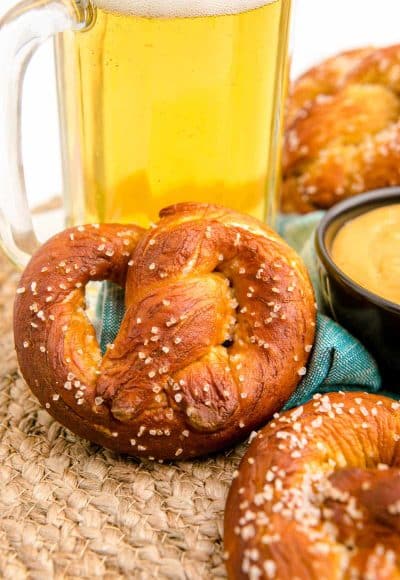Close up of a soft pretzel leaning against a mug of beer.