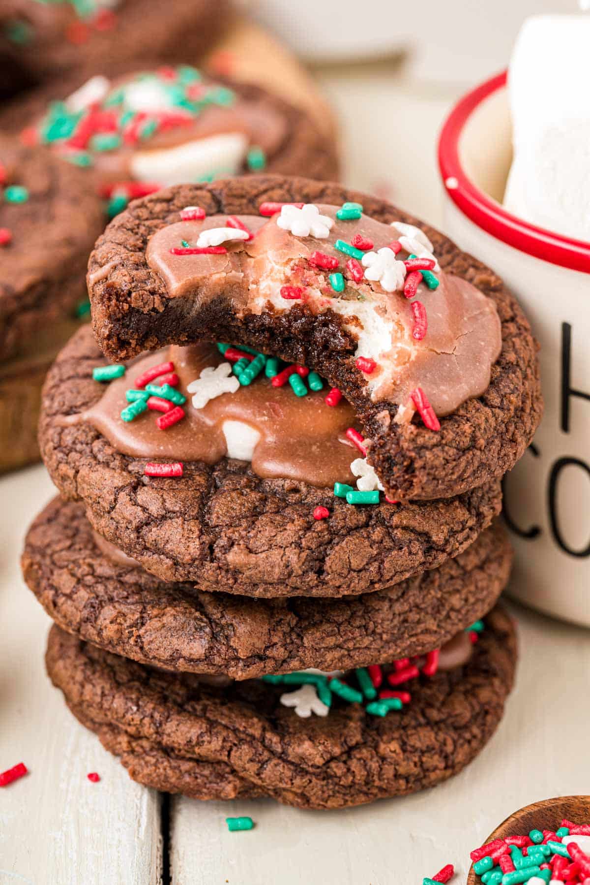 A stack of hot chocolate cookies next to a mug.