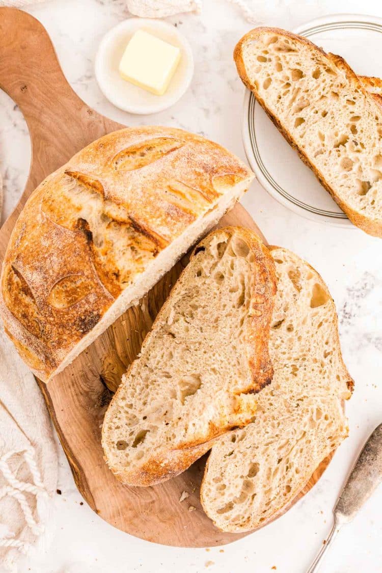 Overhead photo of a loaf of sourdough bread on a cutting board with slices next to it.