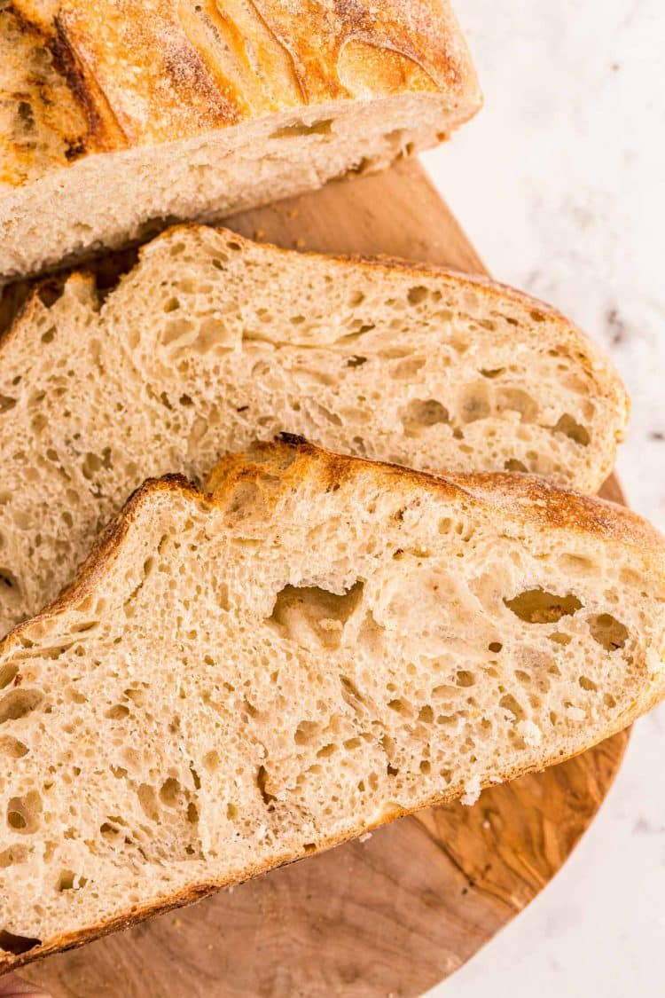 Overhead photo of a loaf of sourdough bread on a cutting board with slices next to it.