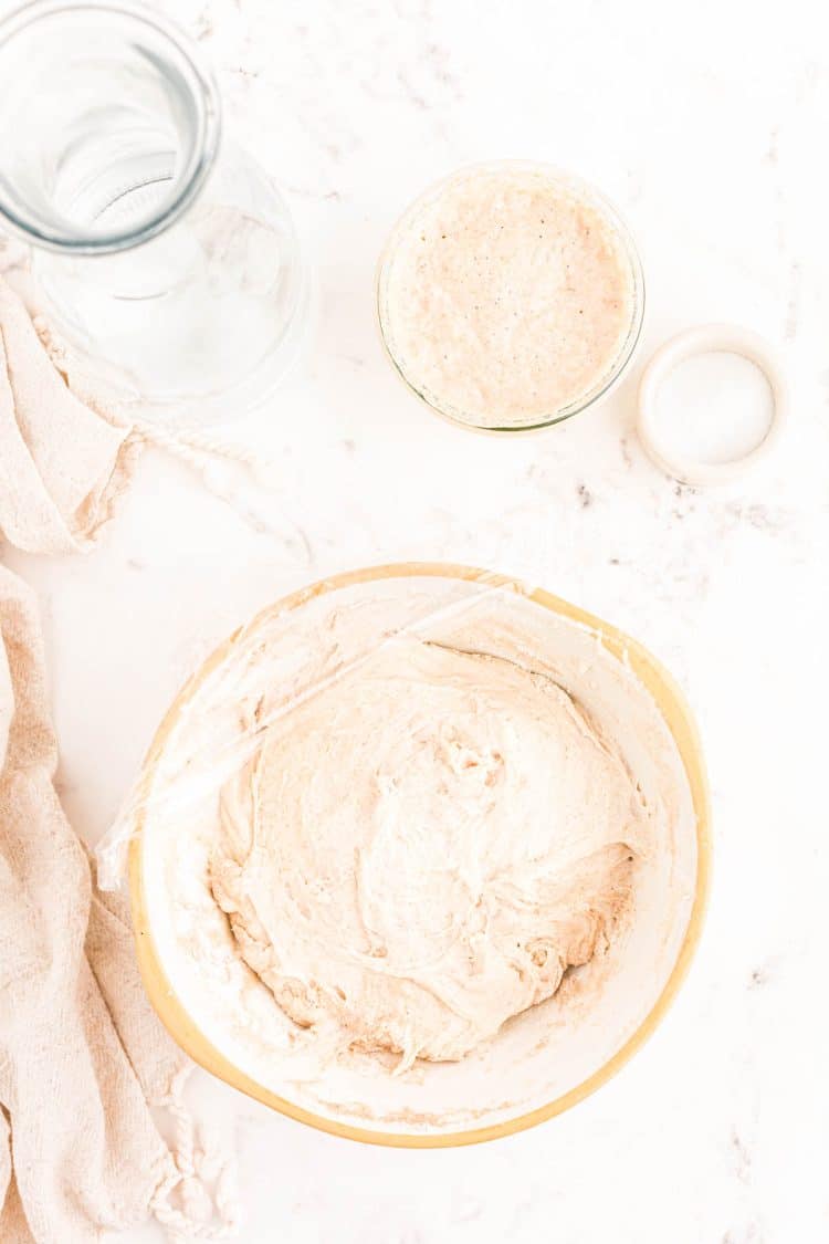 Dough in a mixing bowl ready to be covered with plastic wrap.