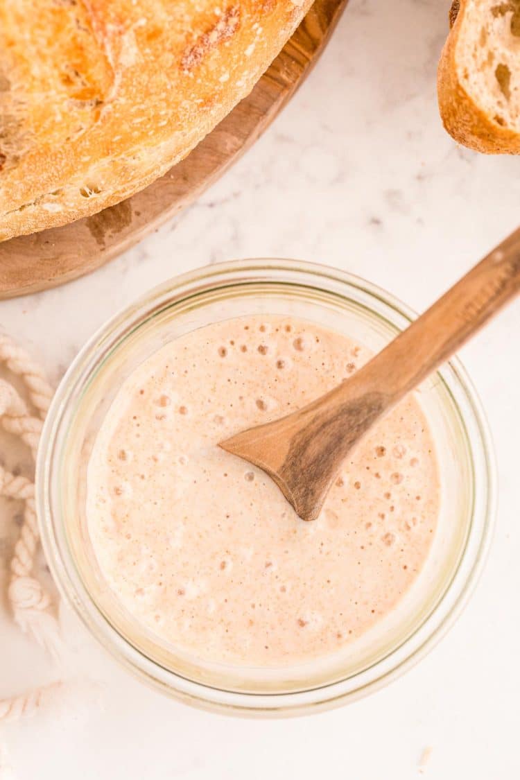 Overhead photo of a jar with sourdough starter in it with sourdough bread to the side of it.