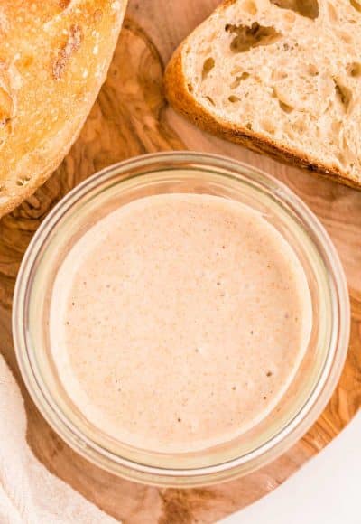 Overhead photo of a jar with sourdough starter in it with sourdough bread to the side of it.