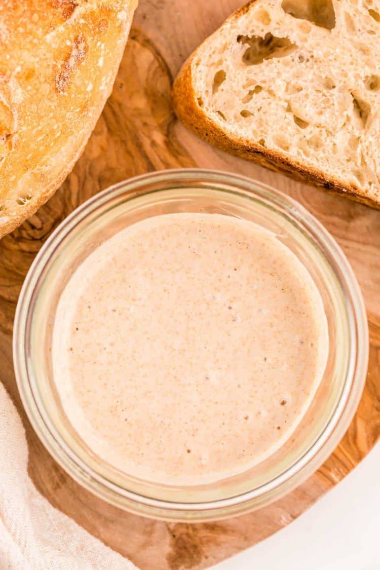 Overhead photo of a jar with sourdough starter in it with sourdough bread to the side of it.