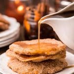 Mexican Bunuelos with syrup being poured over them on a white plate.