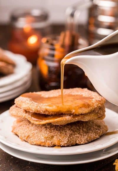 Mexican Bunuelos with syrup being poured over them on a white plate.