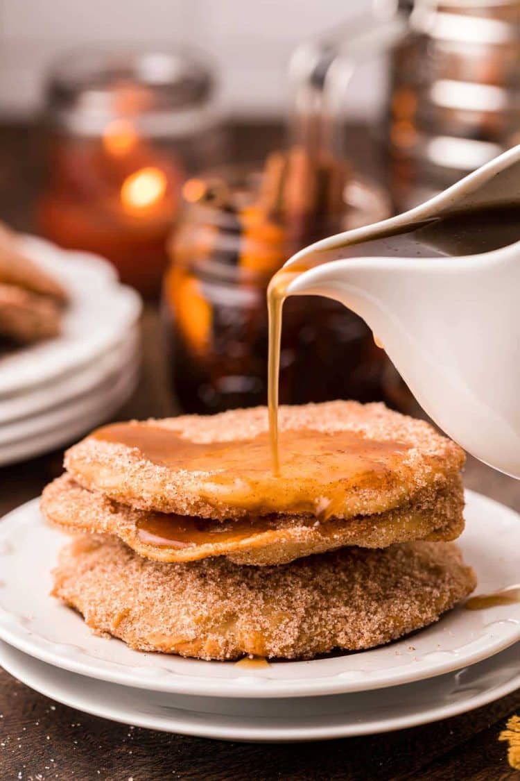 Mexican Bunuelos with syrup being poured over them on a white plate.