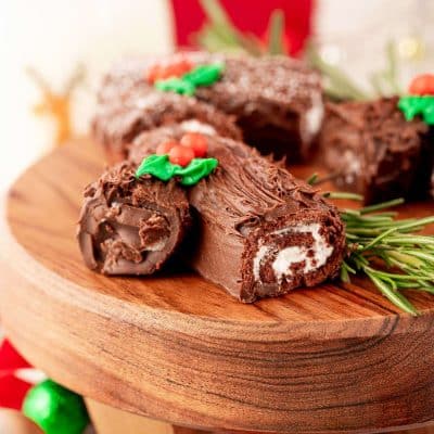 Mini yule log cakes on a wooden cake stand.