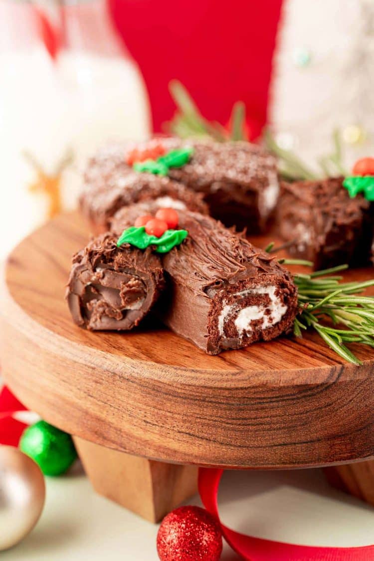Mini yule log cakes on a wooden cake stand.