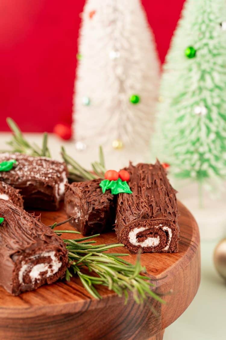 Mini yule logs made from swiss roll cakes on a wooden cake stand.