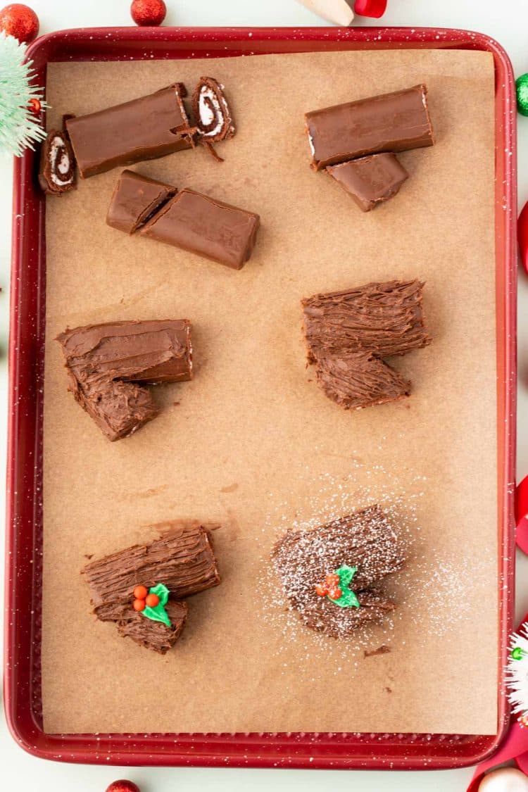 Overhead photo of a red baking sheet lined with parchment paper and swiss rolls being made into mini yule logs.