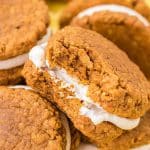 Pumpkin oatmeal cream pies piled on a yellow surface.