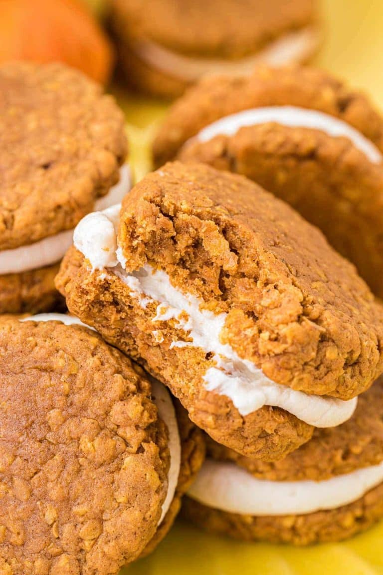 Pumpkin oatmeal cream pies piled on a yellow surface.