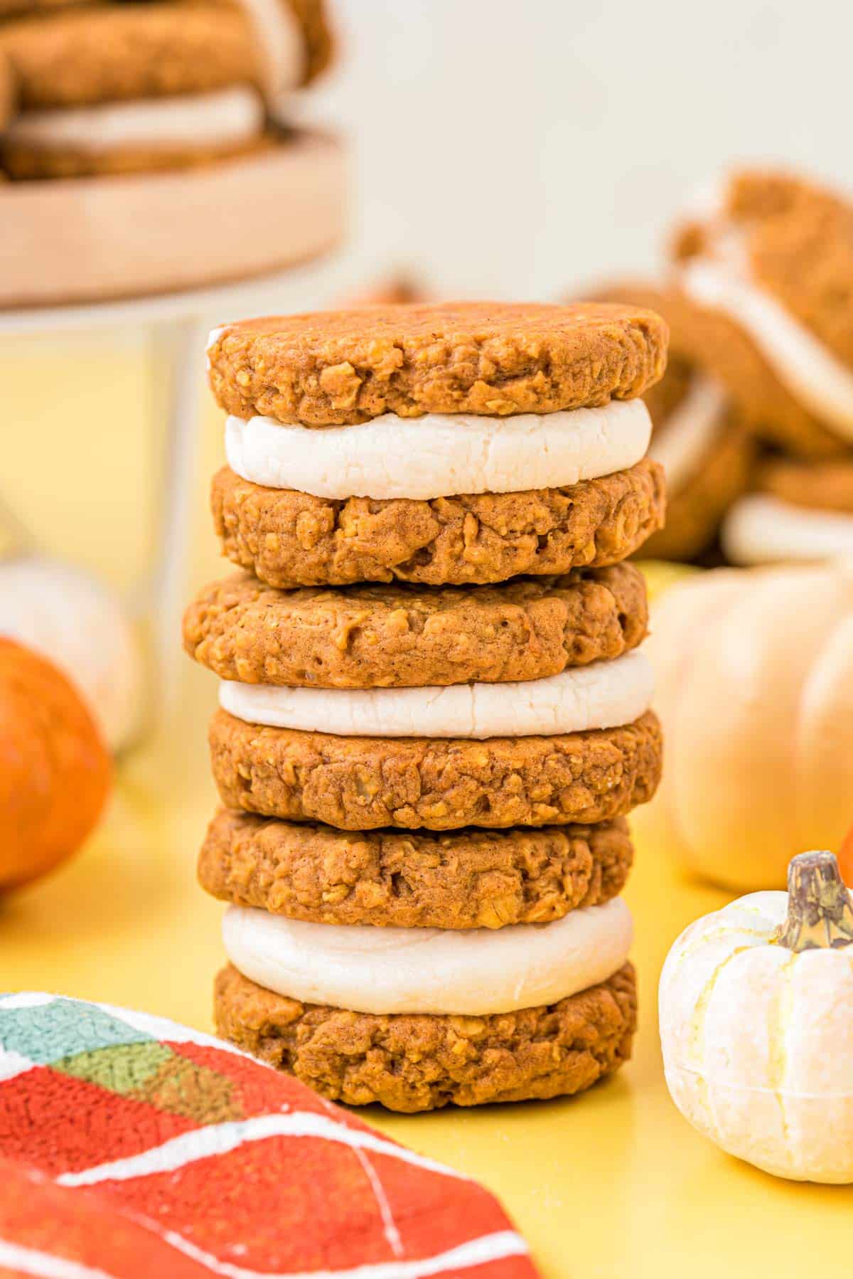 A stack of three pumpkin oatmeal creme pies on a yellow table.