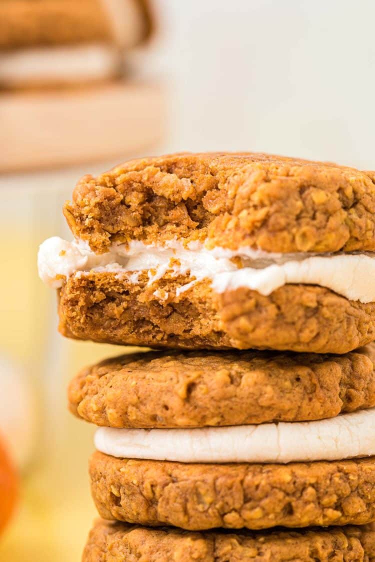 Close up of a stack on pumpkin flavored oatmeal cream pies with the top one missing a bite.