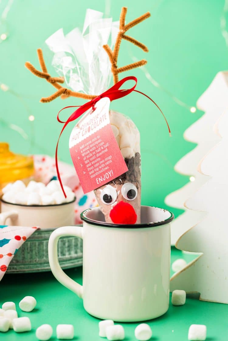 Reindeer hot chocolate cone in a white mug on a green surface.