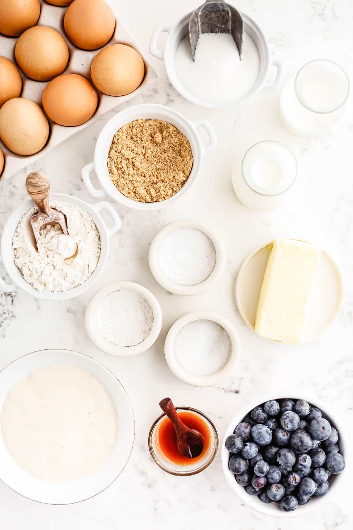 Ingredients to make sourdough blueberry muffins on a white counter.