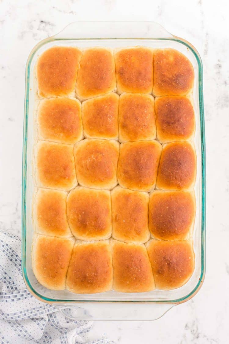 Baked sourdough dinner rolls in a glass baking pan.