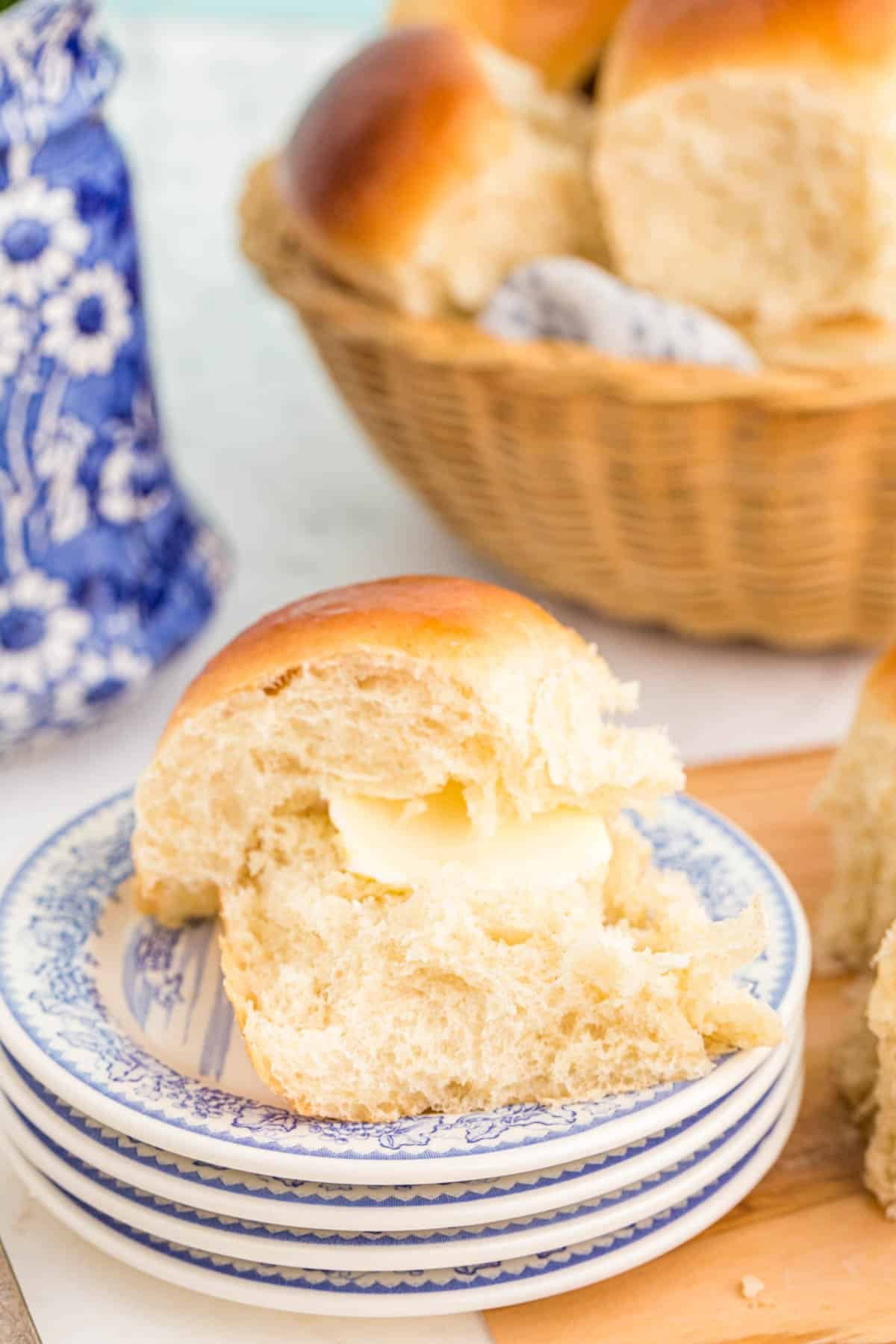 Sourdough dinner roll on a stack of small white and blue plates.