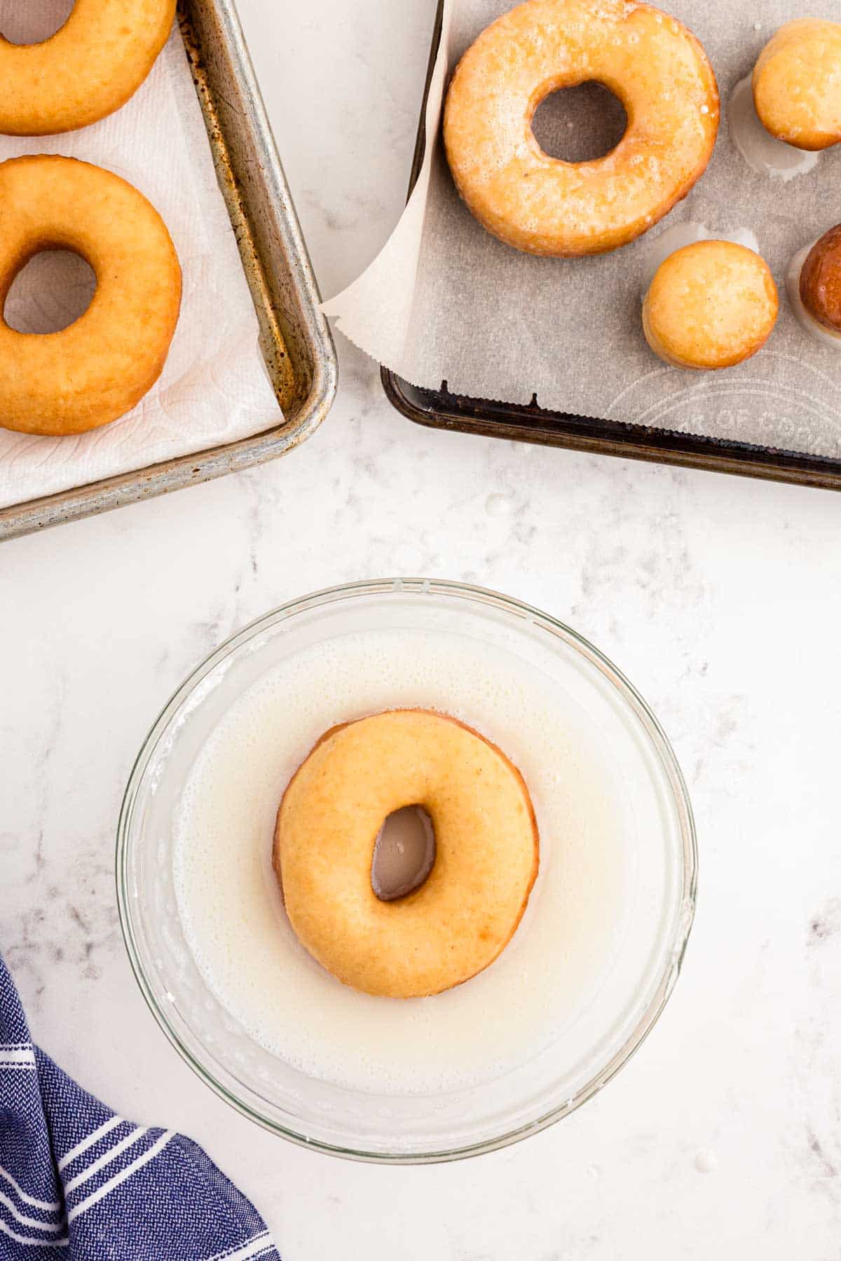 Sourdough donuts being dipped in glaze.