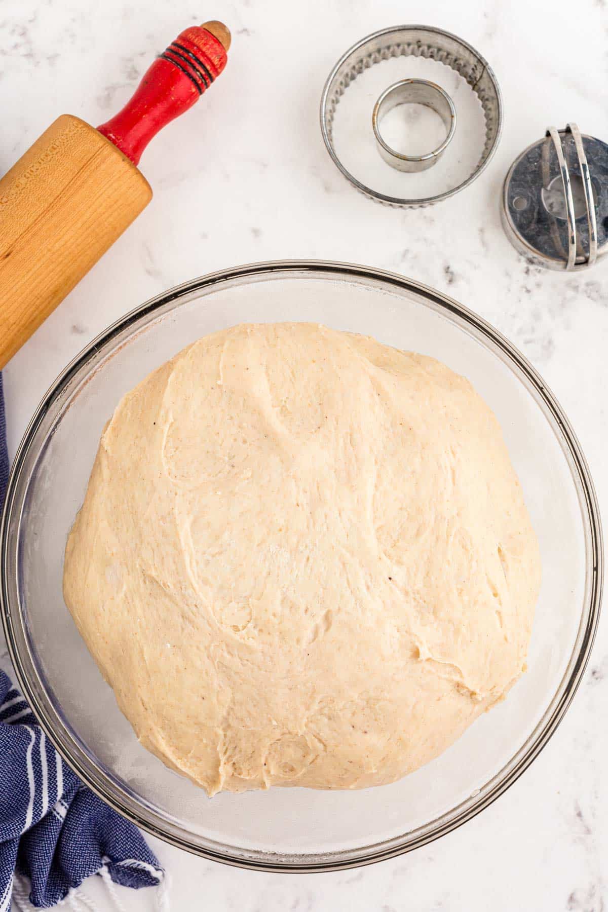 Donut dough proofed in a glass bowl.