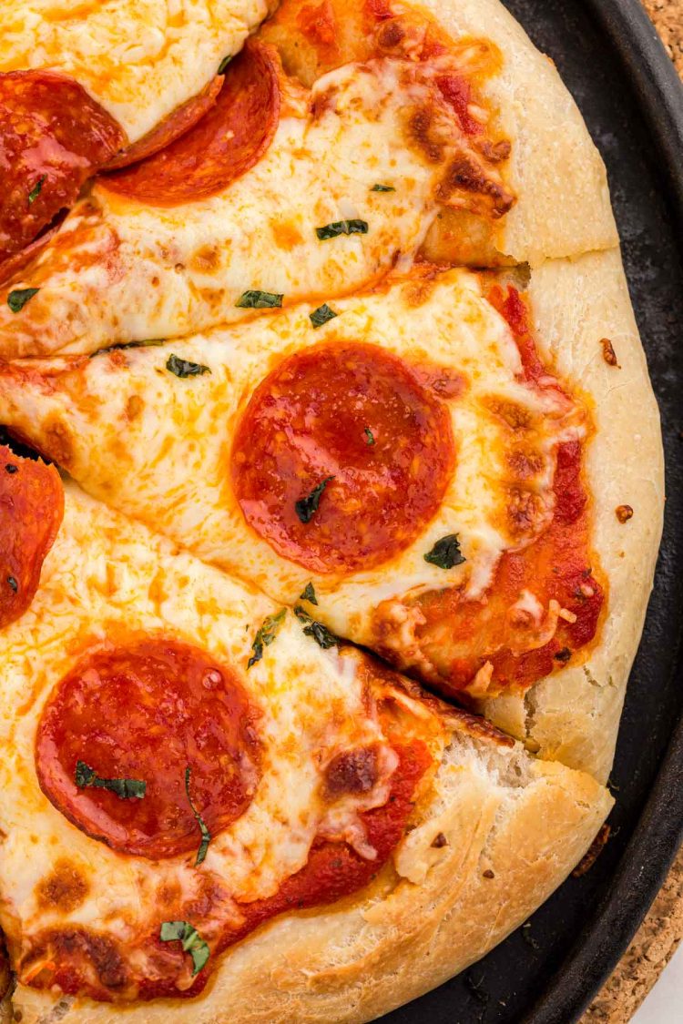 Overhead photo of pizza on a pizza stone made with sourdough discard.