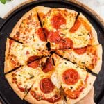 Overhead photo of a sourdough pizza sliced on a pizza stone.