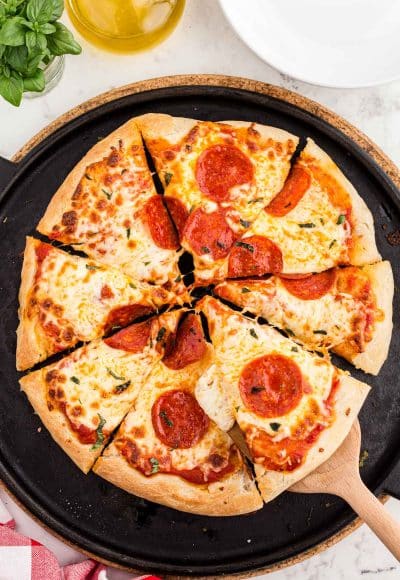 Overhead photo of a sourdough pizza sliced on a pizza stone.