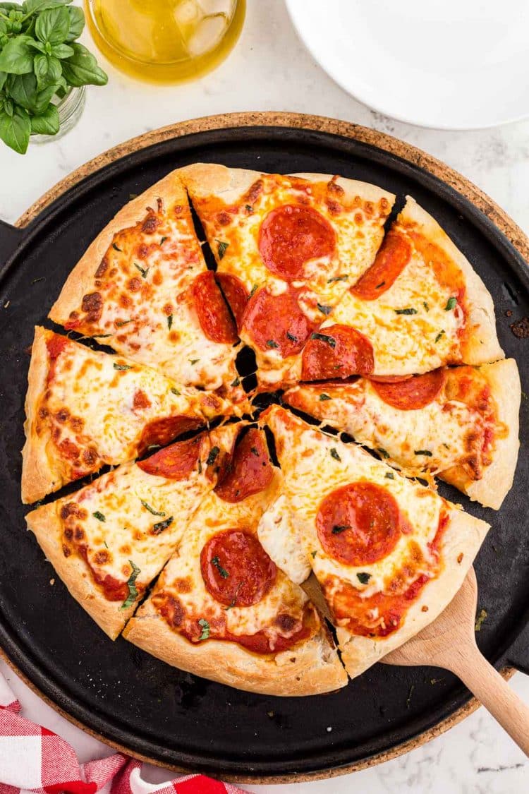 Overhead photo of a sourdough pizza sliced on a pizza stone.