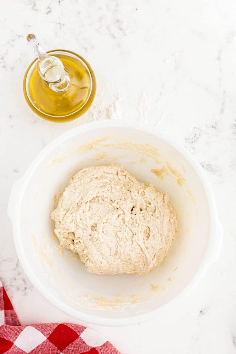 Sourdough pizza dough in a white bowl.