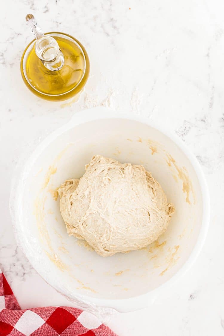 Sourdough pizza dough in a white bowl.