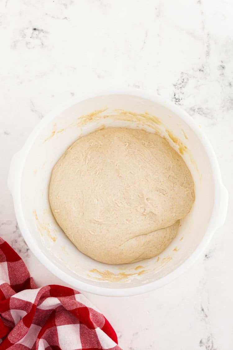 Sourdough pizza dough proofing in a white bowl.