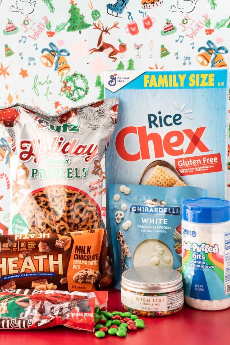 Ingredients to make Christmas Chex Snack Mix on a red table.