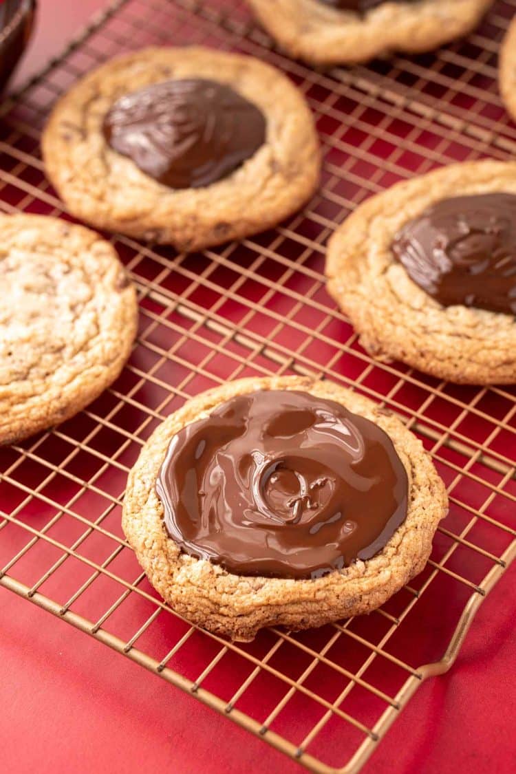 Melted chocolate on top of a cookie on a wire rack.