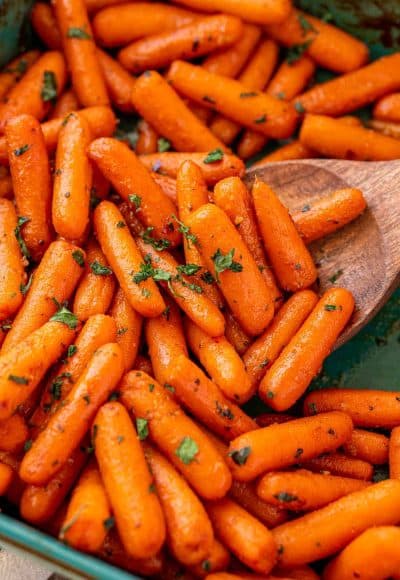 Close up of roasted glazed carrots in a teal baking dish.