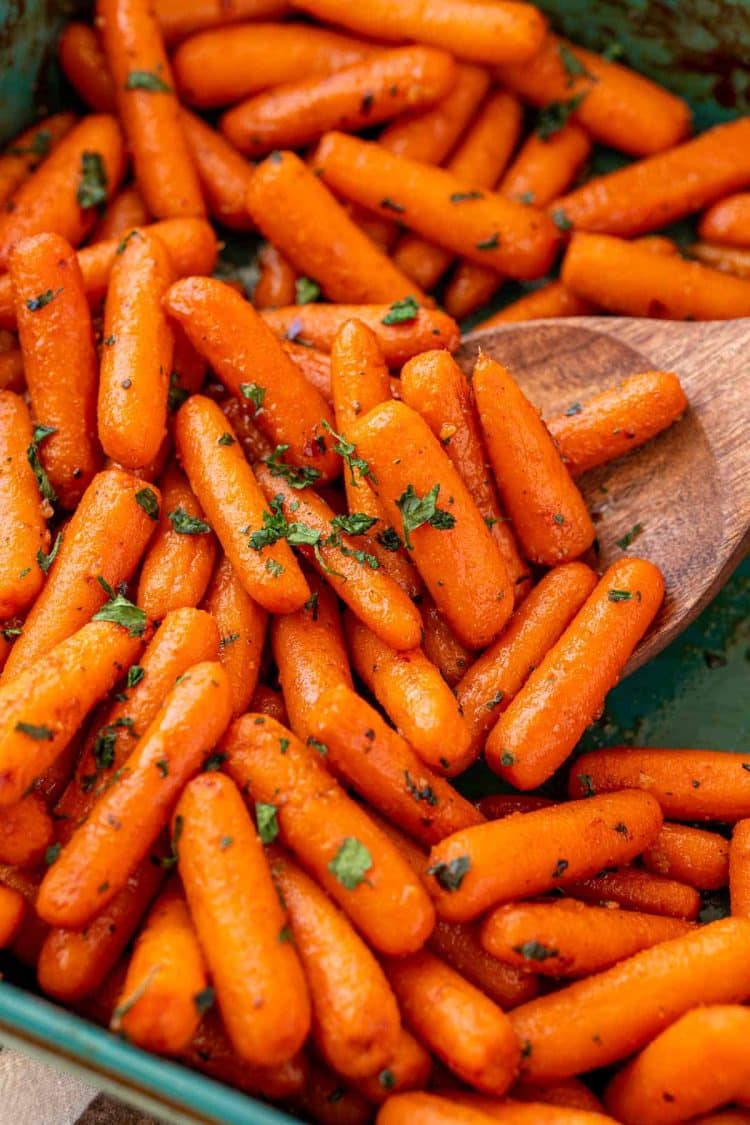 Close up of roasted glazed carrots in a teal baking dish.