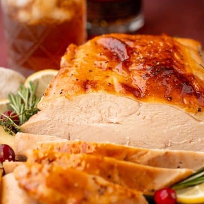 A partially carved glazed turkey breast on a platter.