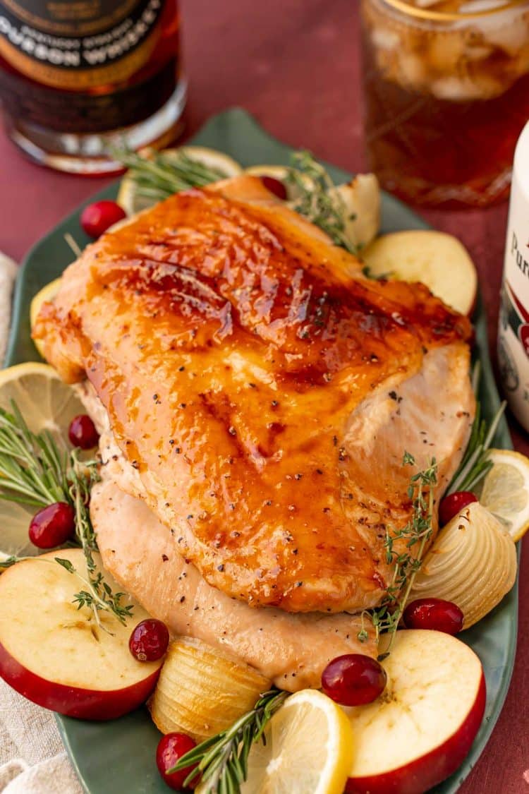 A boneless glazed turkey breast on a platter ready to be carved.
